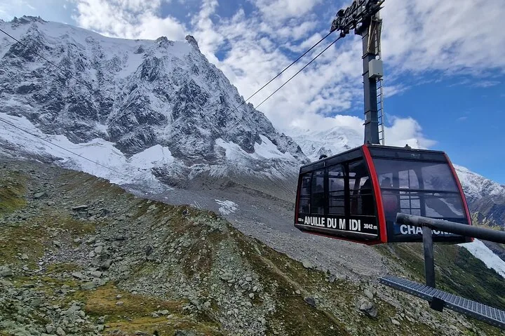 Red cable car approaching Aiguille du Midi with snow-capped mountains