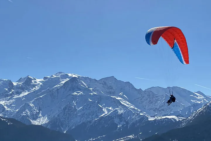 Person paragliding over snowy mountain peaks near Monte Bianco